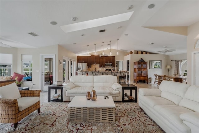 living room featuring ceiling fan and lofted ceiling with skylight