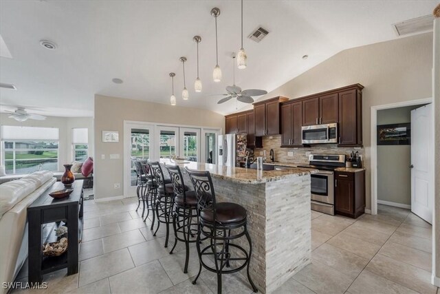 1512 SW 4th Ct, Cape Coral, FL 33991 - kitchen featuring appliances with stainless steel finishes, ceiling fan, dark brown cabinetry, decorative backsplash, and a breakfast bar