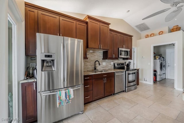 kitchen with light stone countertops, stainless steel appliances, vaulted ceiling, and sink