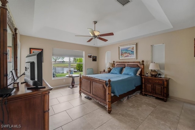 tiled bedroom with a tray ceiling and ceiling fan