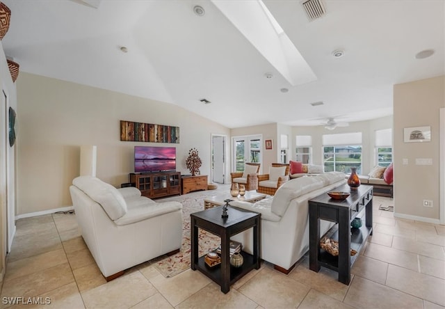 tiled living room with vaulted ceiling with skylight, ceiling fan, and a wealth of natural light