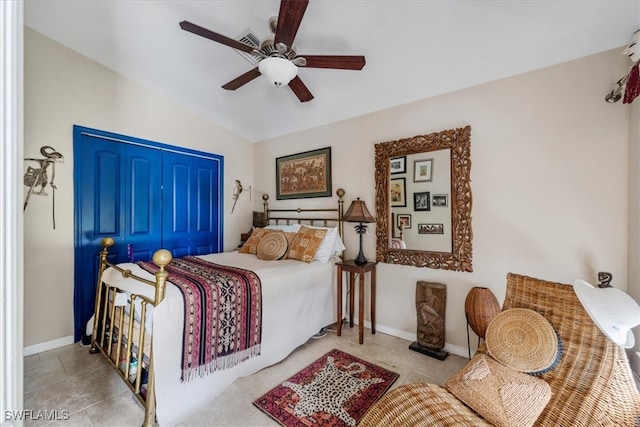 tiled bedroom with ceiling fan, vaulted ceiling, and a closet