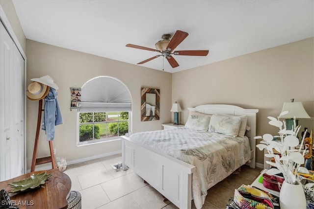 bedroom with ceiling fan, light tile patterned floors, and a closet