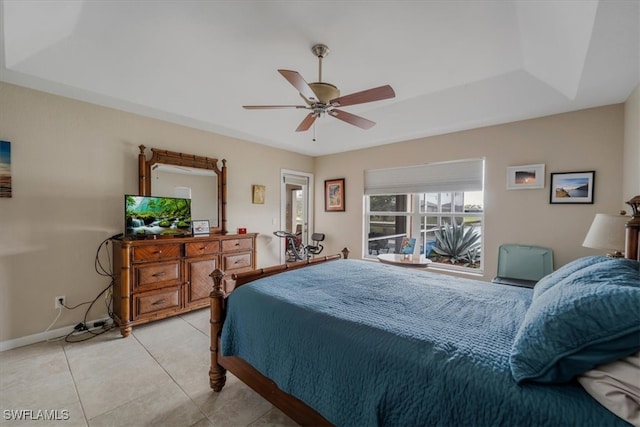 bedroom featuring a raised ceiling, ceiling fan, and light tile patterned flooring