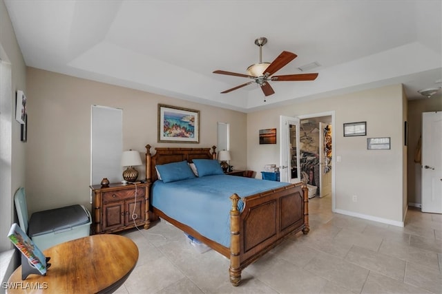 tiled bedroom with a raised ceiling, a walk in closet, ceiling fan, and a closet