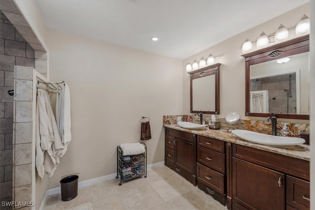 bathroom featuring tile patterned flooring, vanity, and a tile shower