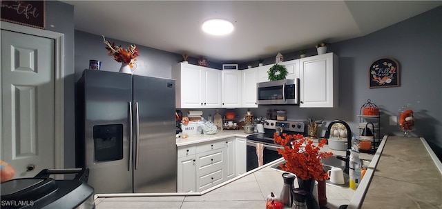 kitchen featuring white cabinetry, stainless steel appliances, and light tile patterned flooring