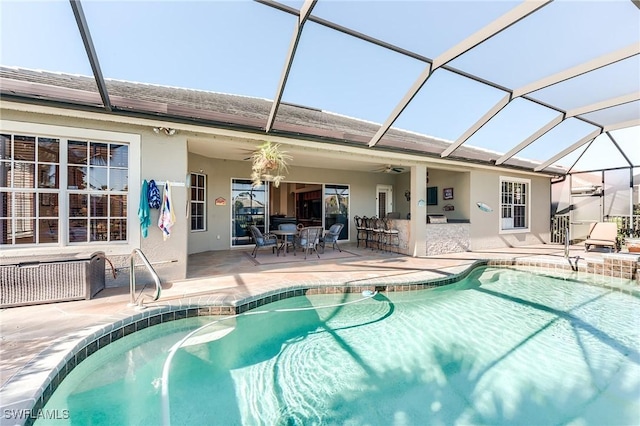 view of swimming pool featuring a lanai, ceiling fan, a patio area, and a bar