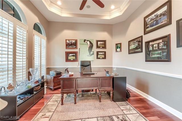 office space featuring wood-type flooring, a raised ceiling, ceiling fan, and ornamental molding