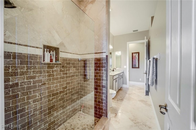 bathroom with a tile shower, vanity, and toilet