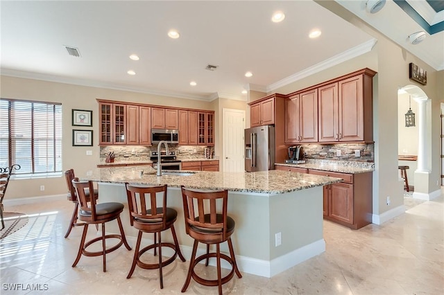 kitchen with a large island, ornamental molding, light stone counters, and appliances with stainless steel finishes