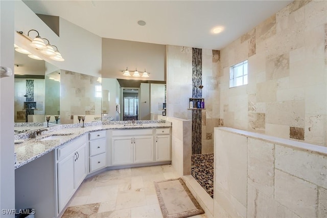 bathroom featuring walk in shower, vanity, and tile walls