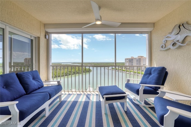 sunroom with a water view and ceiling fan