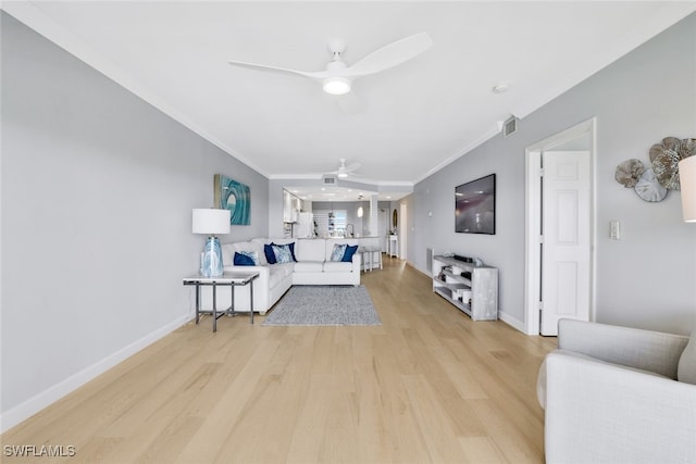 living room with crown molding, ceiling fan, and light wood-type flooring