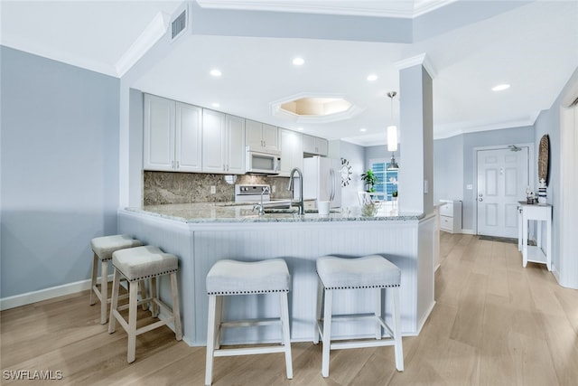 kitchen with white appliances, light stone counters, decorative backsplash, decorative light fixtures, and kitchen peninsula