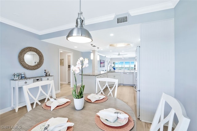 dining area with ornamental molding, sink, and light hardwood / wood-style flooring