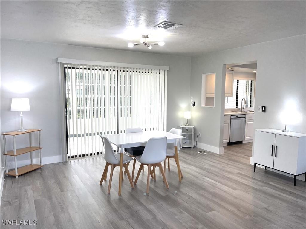 dining space with sink, light hardwood / wood-style flooring, and a textured ceiling