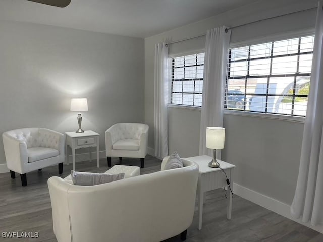 sitting room with ceiling fan and dark wood-type flooring