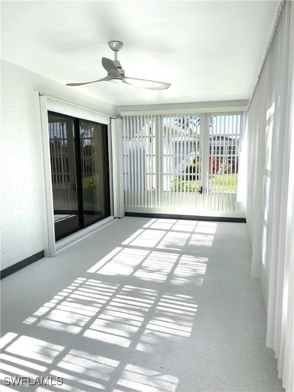 unfurnished sunroom with ceiling fan