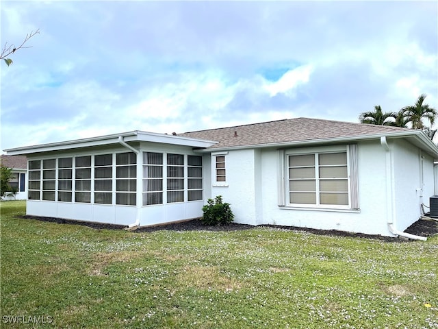 rear view of house featuring central AC, a sunroom, and a yard