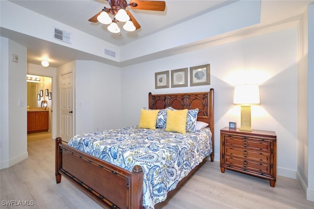 bedroom featuring light wood-type flooring, baseboards, ensuite bath, and a ceiling fan