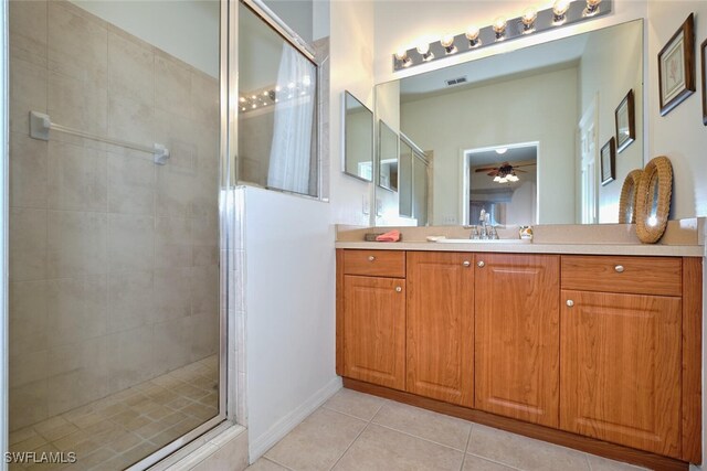 bathroom featuring tile patterned flooring, a shower stall, ceiling fan, vanity, and baseboards