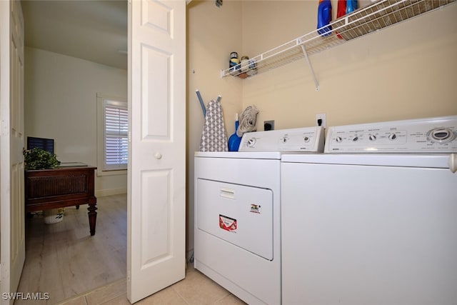 clothes washing area with washer and clothes dryer and light wood-type flooring