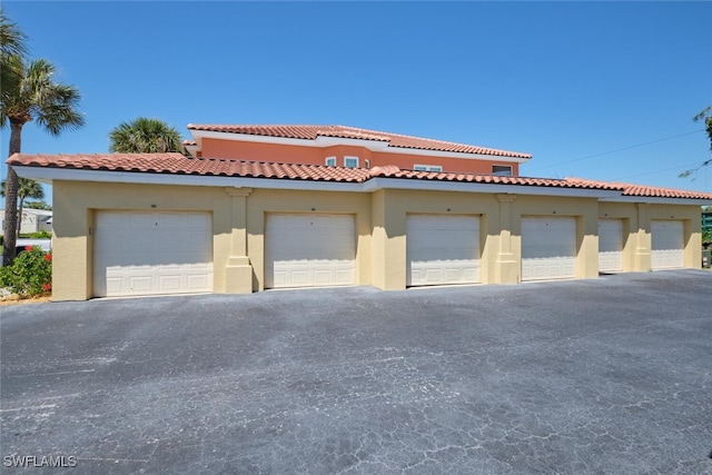 view of front facade with community garages, stucco siding, and a tile roof