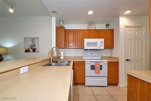 kitchen featuring white appliances, rail lighting, light tile patterned floors, and sink