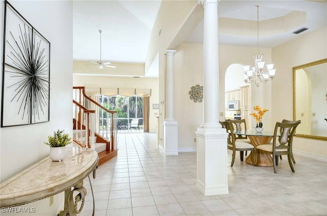 interior space featuring ceiling fan with notable chandelier, light tile patterned flooring, and a high ceiling