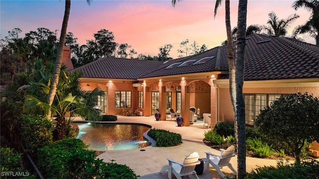 back house at dusk featuring a patio area