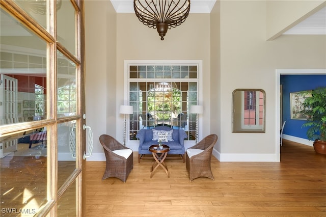 sitting room with ornamental molding and light wood-type flooring