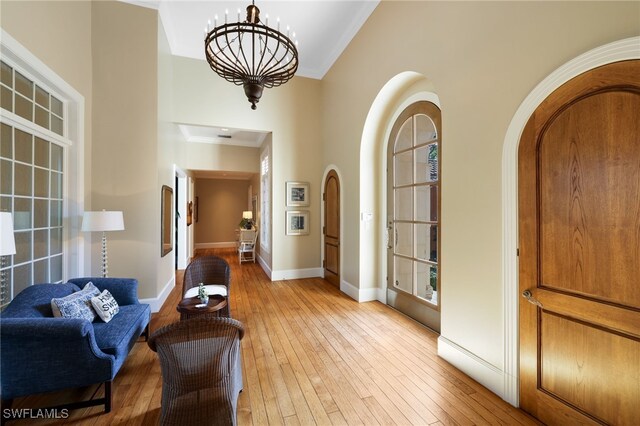 foyer featuring light hardwood / wood-style flooring, high vaulted ceiling, and an inviting chandelier