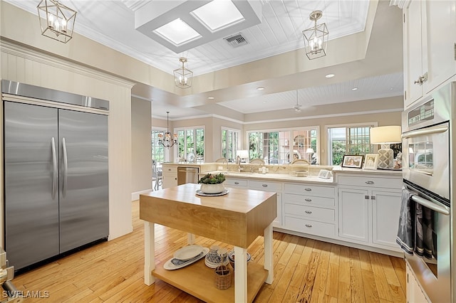 kitchen featuring white cabinets, a center island, stainless steel appliances, and light hardwood / wood-style floors