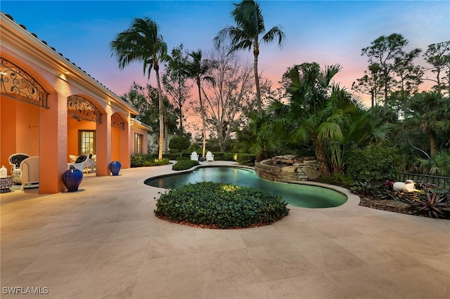 pool at dusk featuring a patio