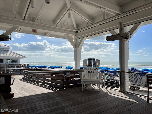 wooden deck featuring a beach view and a water view