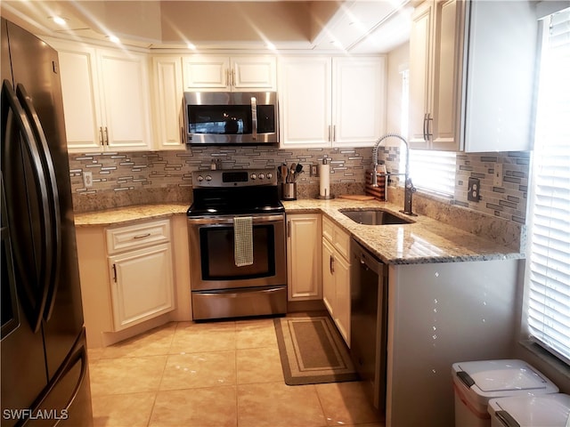 kitchen featuring sink, light tile patterned floors, tasteful backsplash, light stone counters, and stainless steel appliances