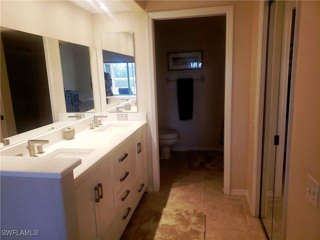 bathroom with toilet, vanity, and tile patterned floors