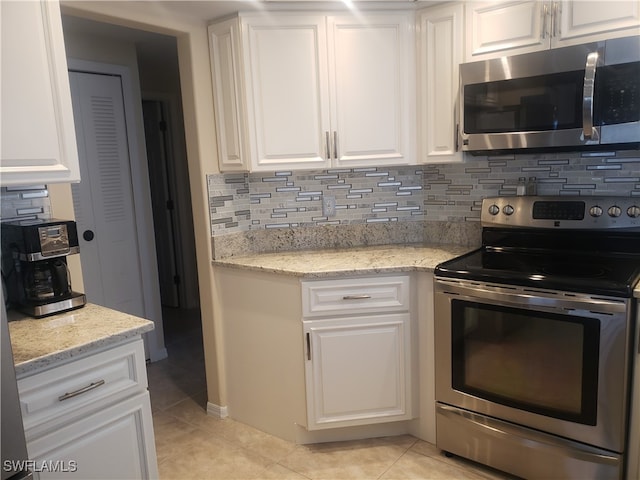 kitchen featuring light tile patterned floors, white cabinetry, appliances with stainless steel finishes, and tasteful backsplash