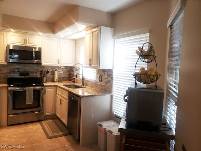 kitchen with a healthy amount of sunlight, sink, light stone countertops, and stainless steel appliances