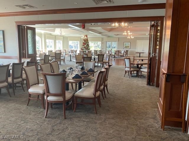 dining area featuring carpet floors, ornamental molding, and a chandelier