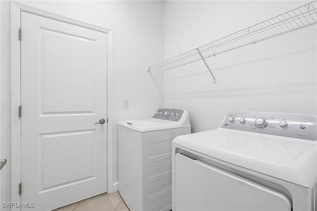 laundry room with washer and clothes dryer and light tile patterned floors