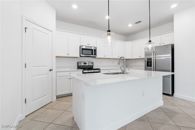 kitchen featuring a kitchen island with sink, appliances with stainless steel finishes, sink, and decorative light fixtures