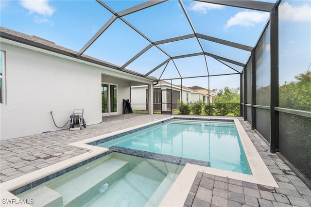 view of pool with glass enclosure, an in ground hot tub, and a patio area