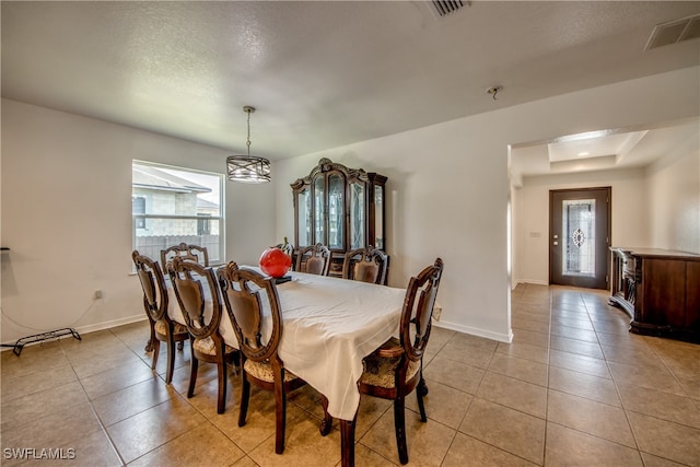 tiled dining area featuring a textured ceiling, an inviting chandelier, and plenty of natural light