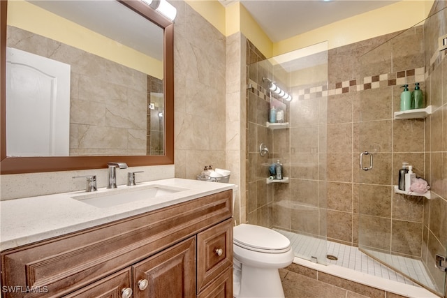 bathroom with a shower with shower door, vanity, toilet, and tile patterned flooring