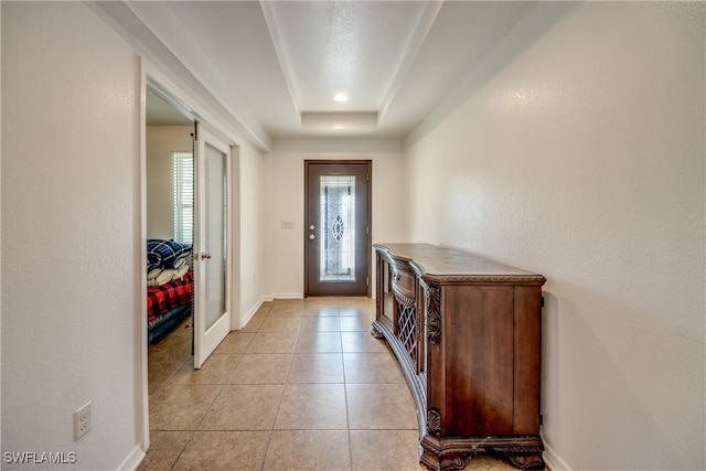 doorway to outside featuring light tile patterned floors and a raised ceiling