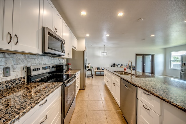 kitchen featuring dark stone countertops, white cabinetry, sink, and stainless steel appliances