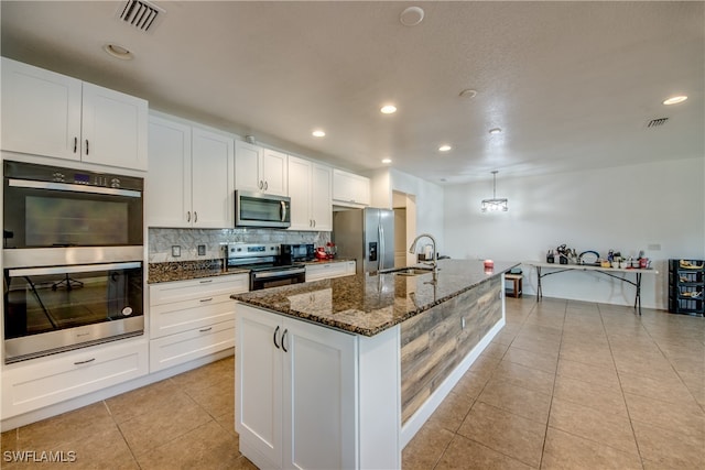 kitchen with stainless steel appliances, white cabinets, sink, and an island with sink