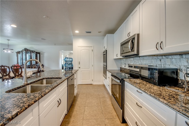 kitchen featuring white cabinets, stainless steel appliances, dark stone counters, and sink